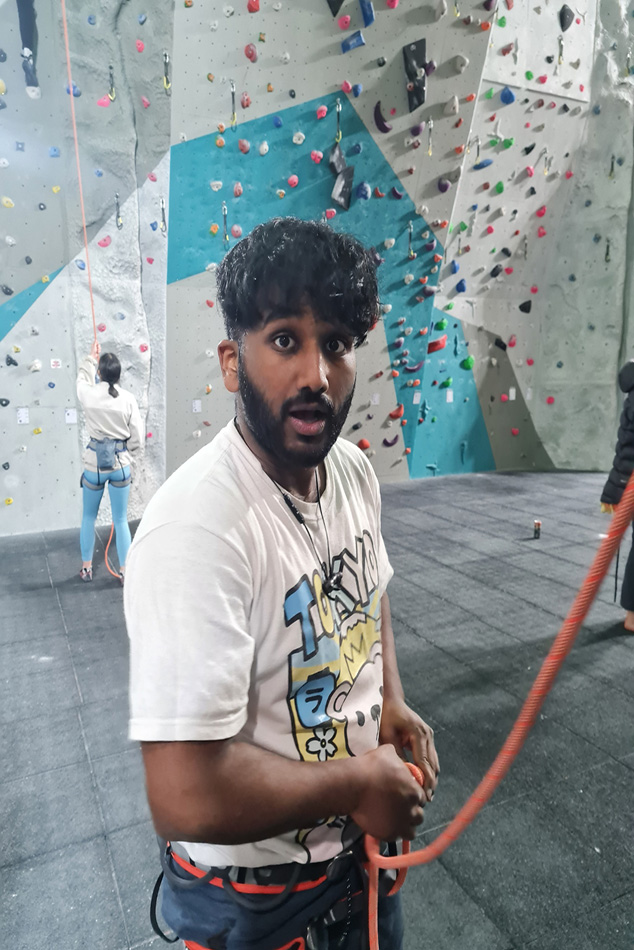 A man looking shocked while untying a orange rope from his harness